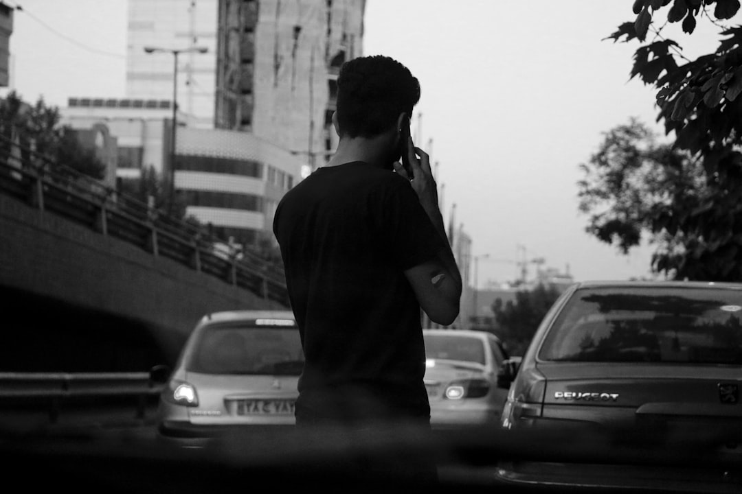 A man standing on the side of a road talking on a cell phone